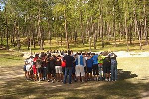 En un prado con un fondo de árboles, grupo de jóvenes en círculo